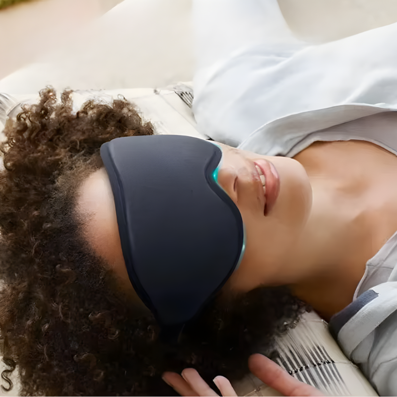 ViSleep™ Blackout 3D sleep mask in black, worn by a person lying down, with a relaxed expression and curly hair.